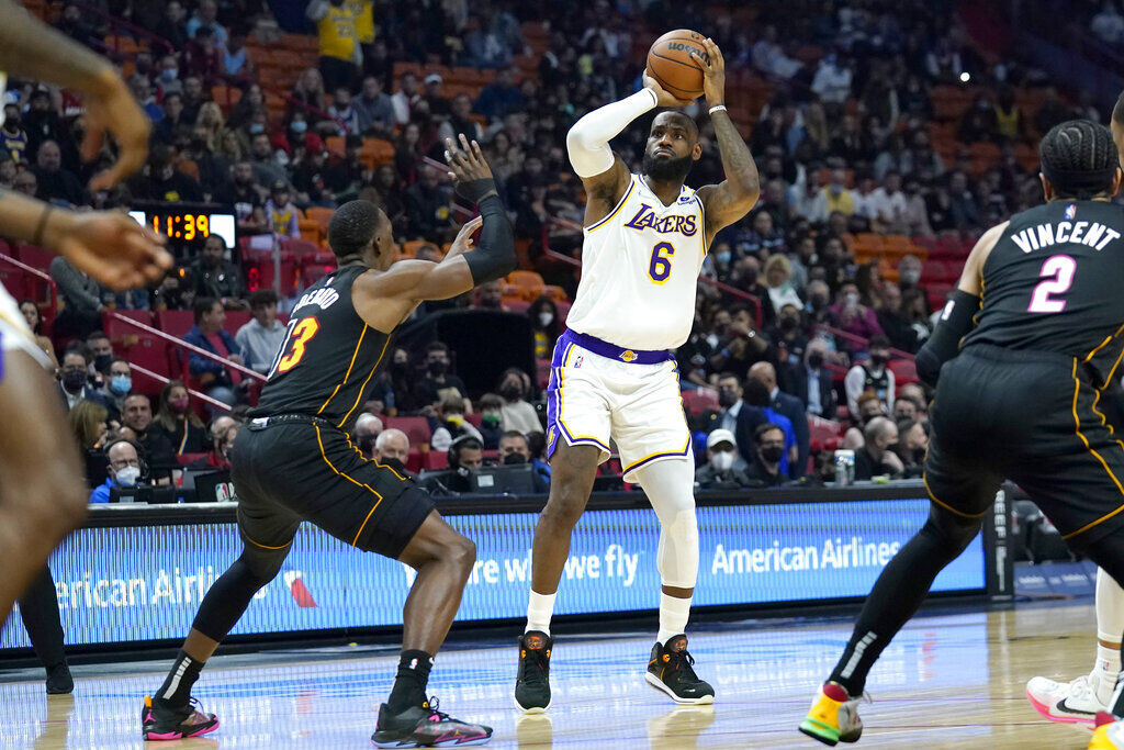 <p>Los Angeles Lakers forward LeBron James (6) attempts a three-point basket as Miami Heat center Bam Adebayo defends during the first half of an NBA basketball game, Sunday, Jan. 23, 2022, in Miami. (AP Photo/Lynne Sladky)</p>