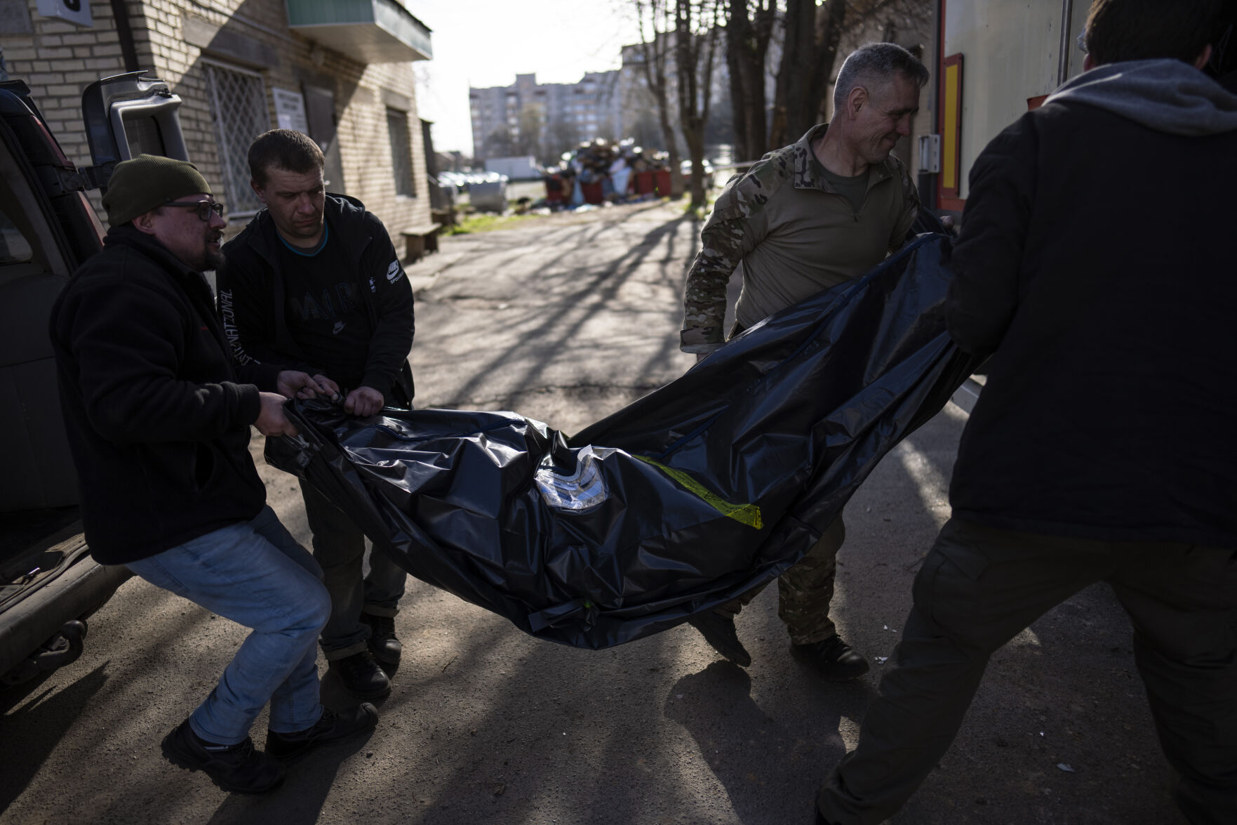 <p>Volunteers carry the body of a man killed during the war to a refrigerated container in Bucha, in the outskirts of Kyiv, Ukraine, Thursday April 14, 2022. (AP Photo/Rodrigo Abd)</p>