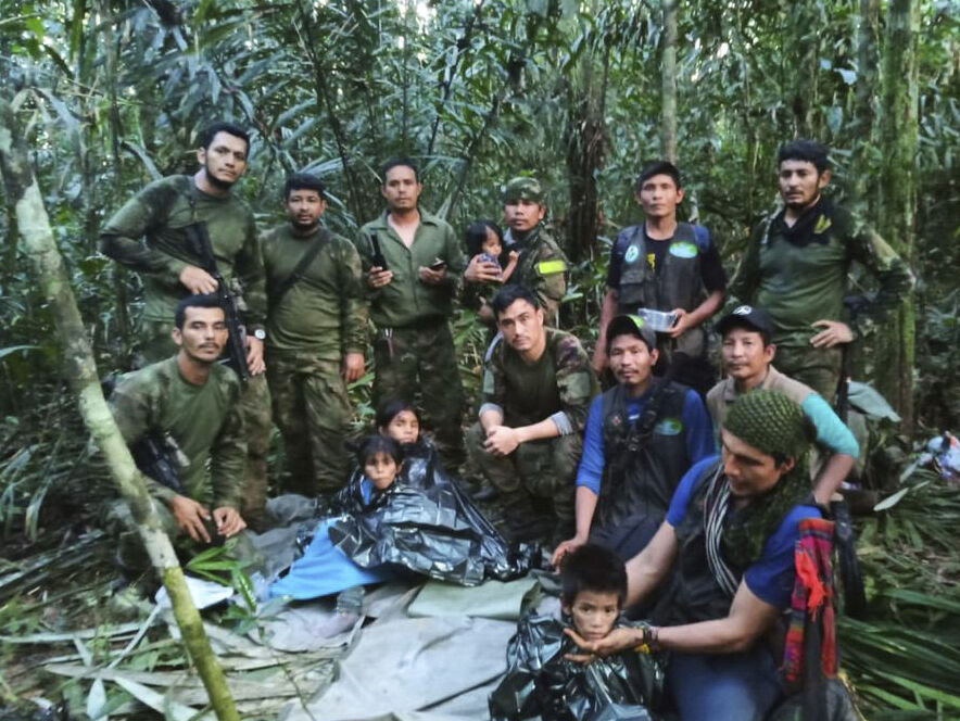 <p>Soldiers and Indigenous men pose for a photo with the four Indigenous children who were missing after a deadly plane crash, Friday in the Solano jungle, Caqueta state, Colombia.</p>