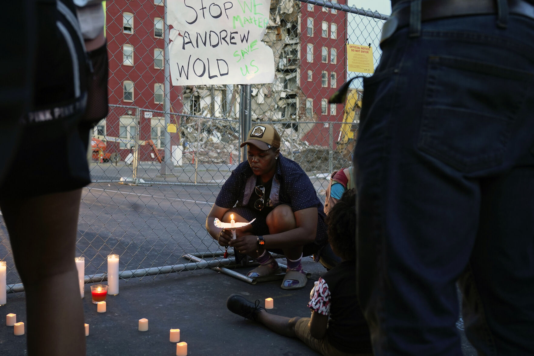 <p>After asking a group of about 50 people gathered for a vigil to remain silent for five minutes Tuesday in honor of the five people still unaccounted for, Raquel Sipp kneels with a candle at the scene of where an apartment building partially collapsed Sunday in Davenport, Iowa. Five residents remain unaccounted for.</p>