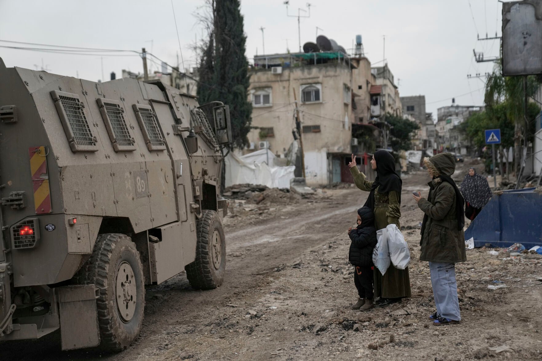 <p>A Palestinian woman flashes a V-sign towards Israeli troops during an army raid in the Tulkarem refugee camp, West Bank, Wednesday, Jan.17, 2024. An Israeli airstrike killed four Palestinians during a raid in the West Bank. The military says it targeted a group of militants who had opened fire and were throwing explosives at Israeli soldiers in the Tulkarem refugee camp. The Palestinian Health Ministry says four people were killed. (AP Photo/Nasser Nasser)</p>