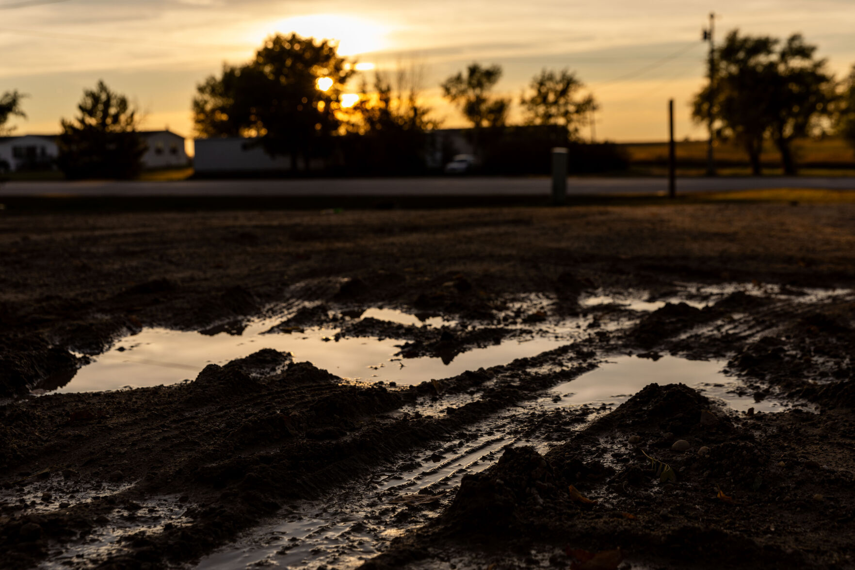 <p>A mud puddle reflects the sunset on the Rosebud Indian Reservation in South Dakota on Monday, Oct. 16, 2023.</p>