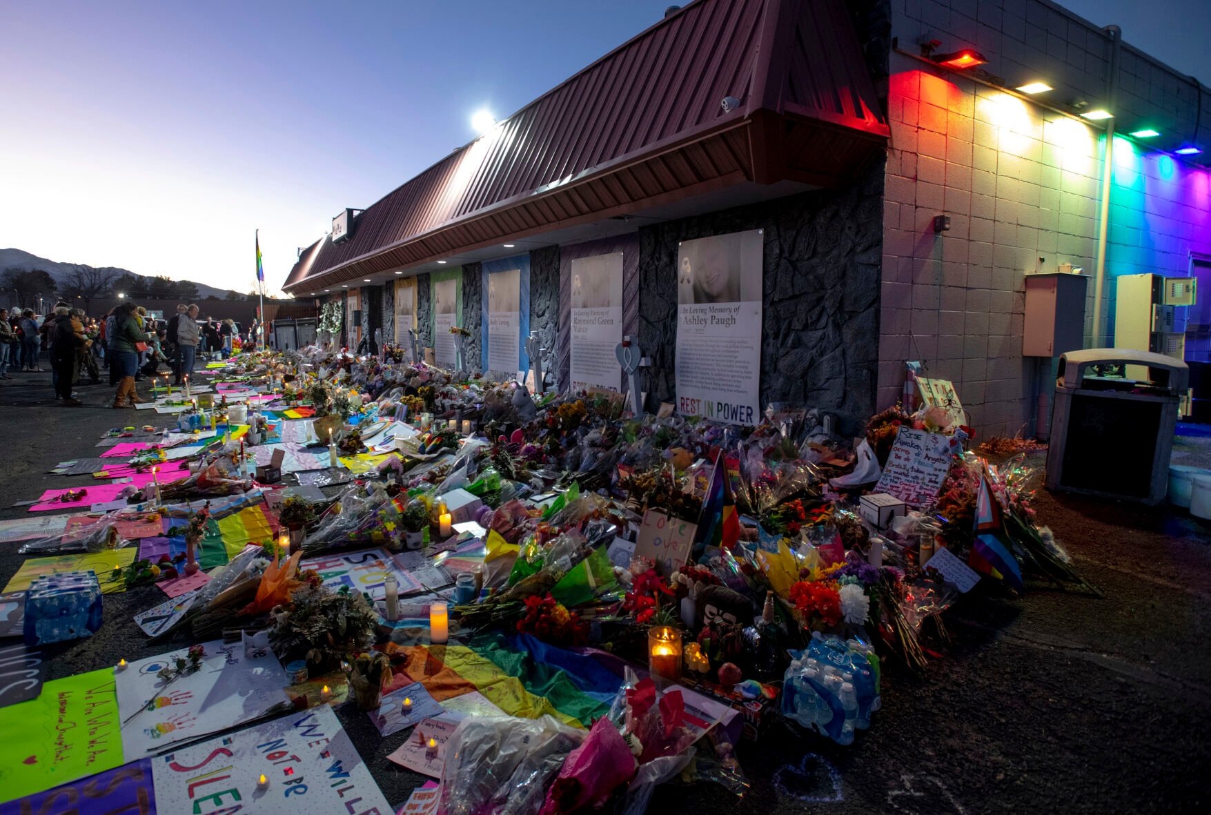<p>File - Mourners gather outside Club Q to visit a memorial, which has been moved from a sidewalk outside of police tape that was surrounding the club, on Friday, Nov. 25, 2022, in Colorado Spring, Colo. The suspect accused of entering the gay nightclub clad in body armor and opening fire with an AR-15-style rifle, killing five people and wounding 17 others, is set to appear in court again Tuesday, Dec. 6 to learn what charges prosecutors will pursue in the attack, including possible hate crime counts. (Parker Seibold/The Gazette via AP, File)</p>