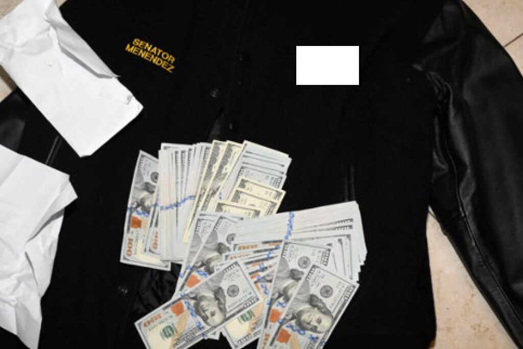 <p>This photo, which was included in an indictment of U.S. Sen. Bob Menendez (D-N.J.), shows a jacket bearing Menendez's name, along with cash from envelops found inside the Jacket during a search by federal agents of the senator's home in Harrison, N.J., in 2022. </p>