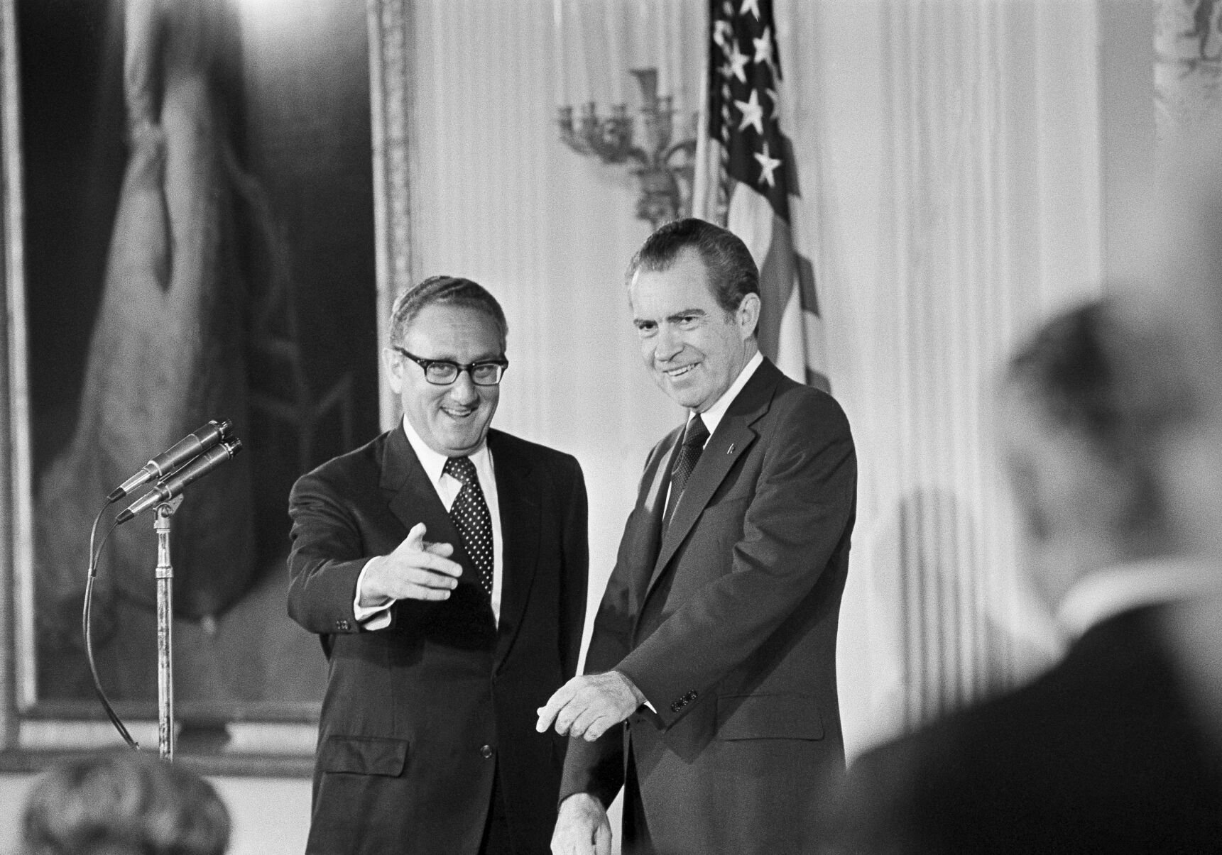 <p>Then-Secretary of State Henry Kissinger, left, gestures to the audience in the East Room of the White House, Sept. 22, 1973, as President Richard Nixon watches, in Washington. Kissinger had just been sworn in.</p>