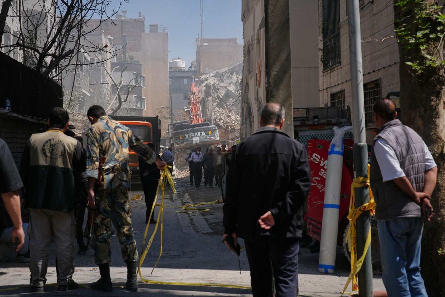 <p>Bystanders watch from a distance as rescue teams and first responders work at the site of a strike that, according to a security official at the scene, destroyed half of the Khorasaniha Synagogue and nearby residential buildings Tuesday in Tehran, Iran. </p>