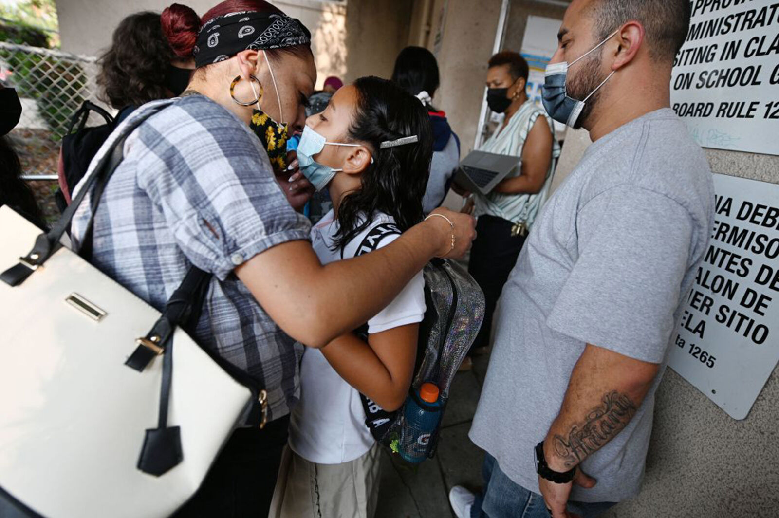 <p>Sophia Cifuentes (left) kisses her daughter Airiany goodbye as she and her husband Jose (right) drop Airiany off for the first day of the school year at Grant Elementary School in Los Angeles, California, August 16, 2021. (Robyn Beck/AFP via Getty Images/TNS)</p>